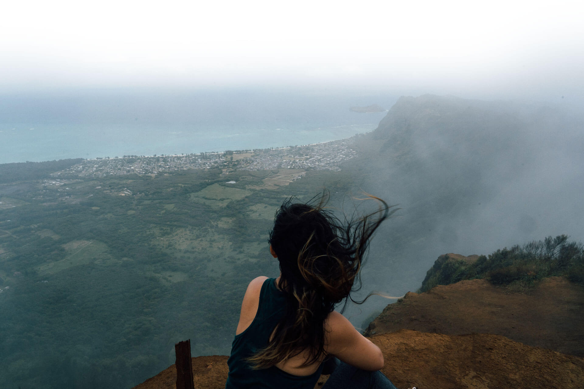 Woman sitting on a mountain on the island of Oahu.