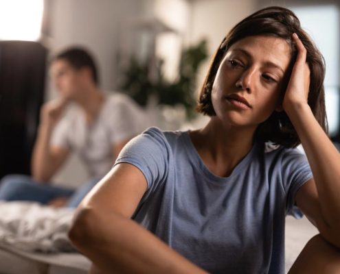 Woman with depression sitting in her living room. Couples therapy or individual therapy sessions can help manage Seasonal Afffective Disorder depression during the holidays.