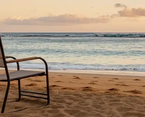A lone chair at the beach representing the loneliness epidemic in Hawaii caused by social isolation, the erosion of Ohana, and the disconnect caused by social media.